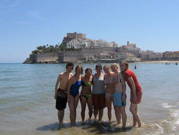 a group of study abroad students is huddled together for a picture in front of a body of water